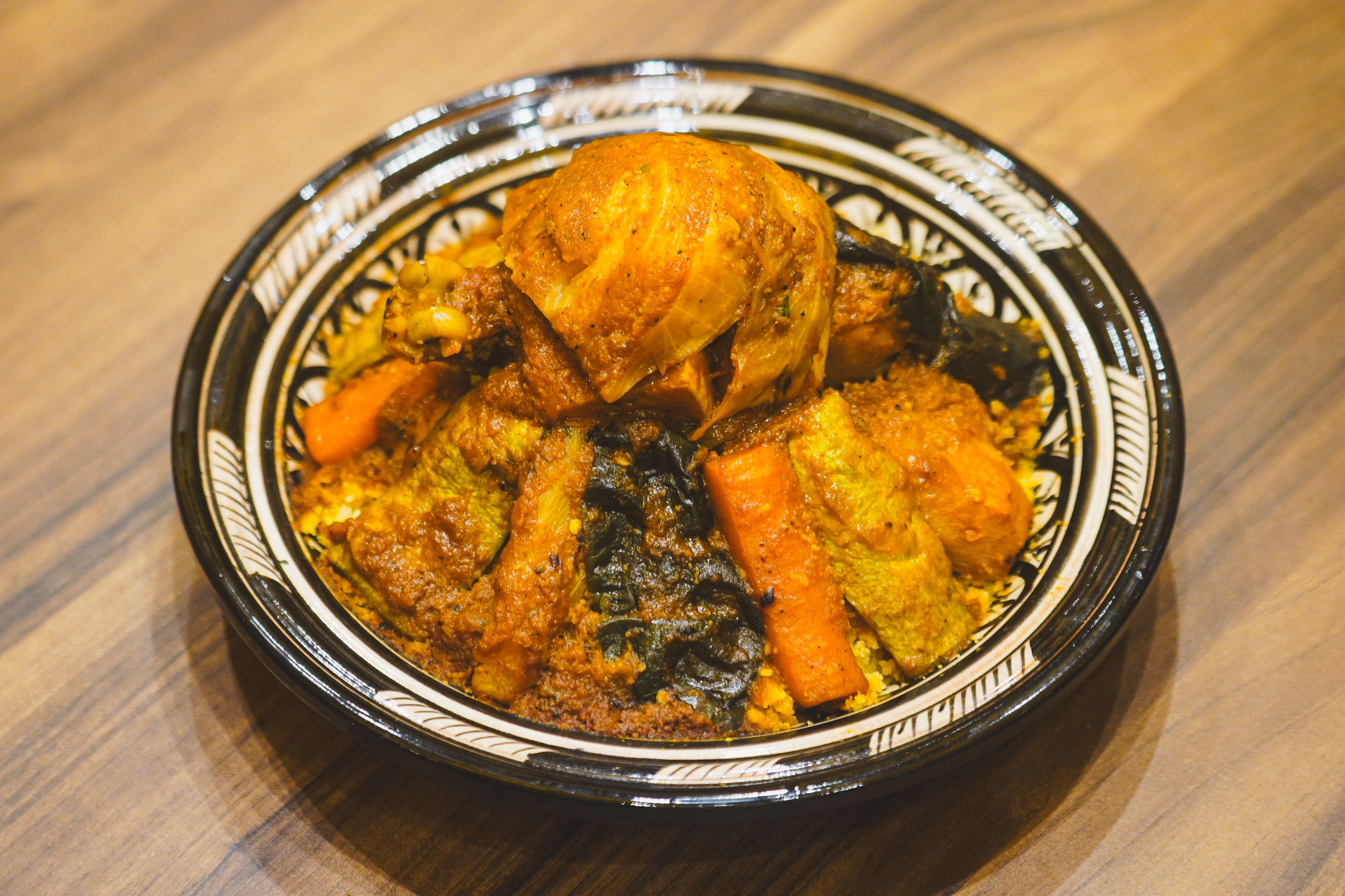 Savor a hearty Moroccan couscous dish with seasoned chicken and vegetables, perfect for cultural cuisine enthusiasts.