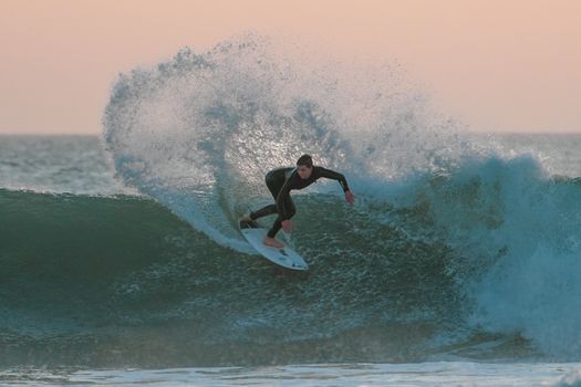 A surfer skillfully rides a wave during sunset at Oued Ed-Dahab beach, showcasing athleticism and adventure.