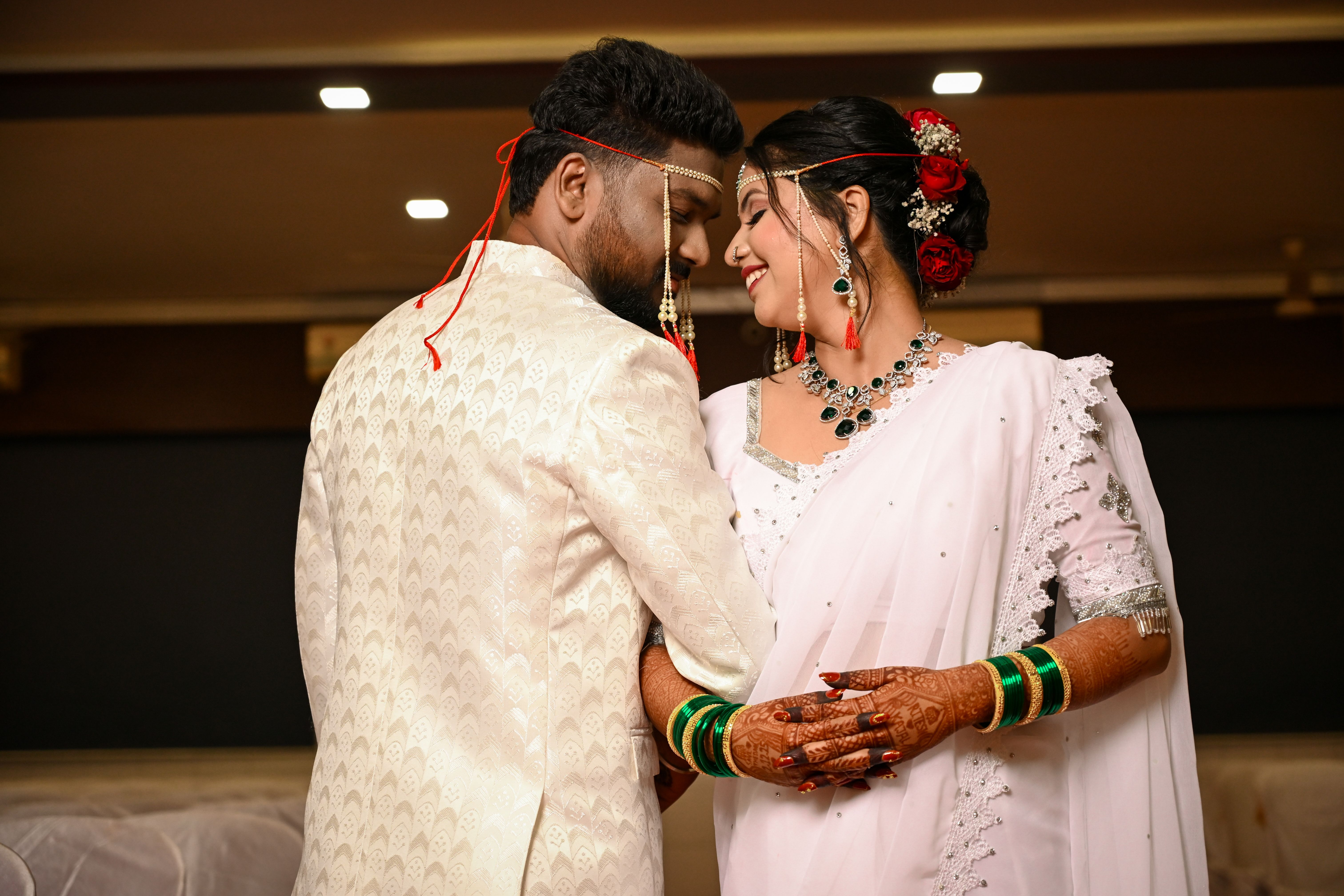 Beautiful Indian couple in traditional attire sharing a moment during their wedding indoors.