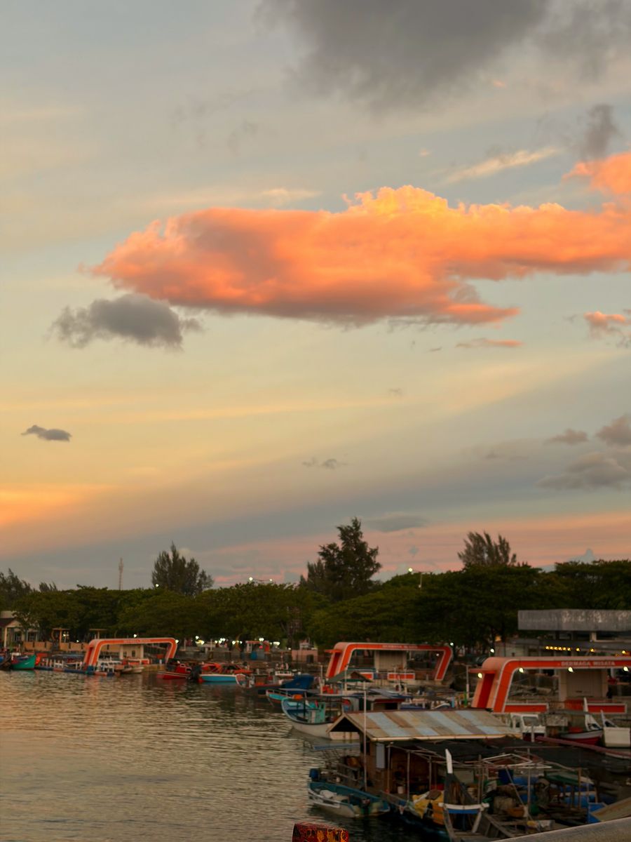 Fishing boats in Banda Aceh harbor under a pink and orange sunset sky