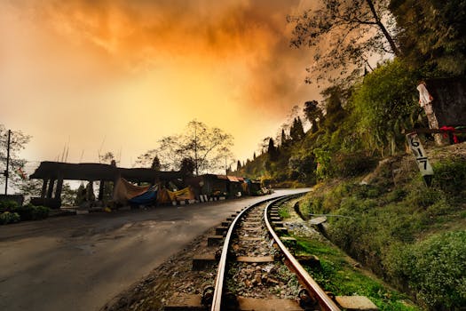 Captivating railway curves through lush Darjeeling landscape at sunset, enhancing the dramatic sky.