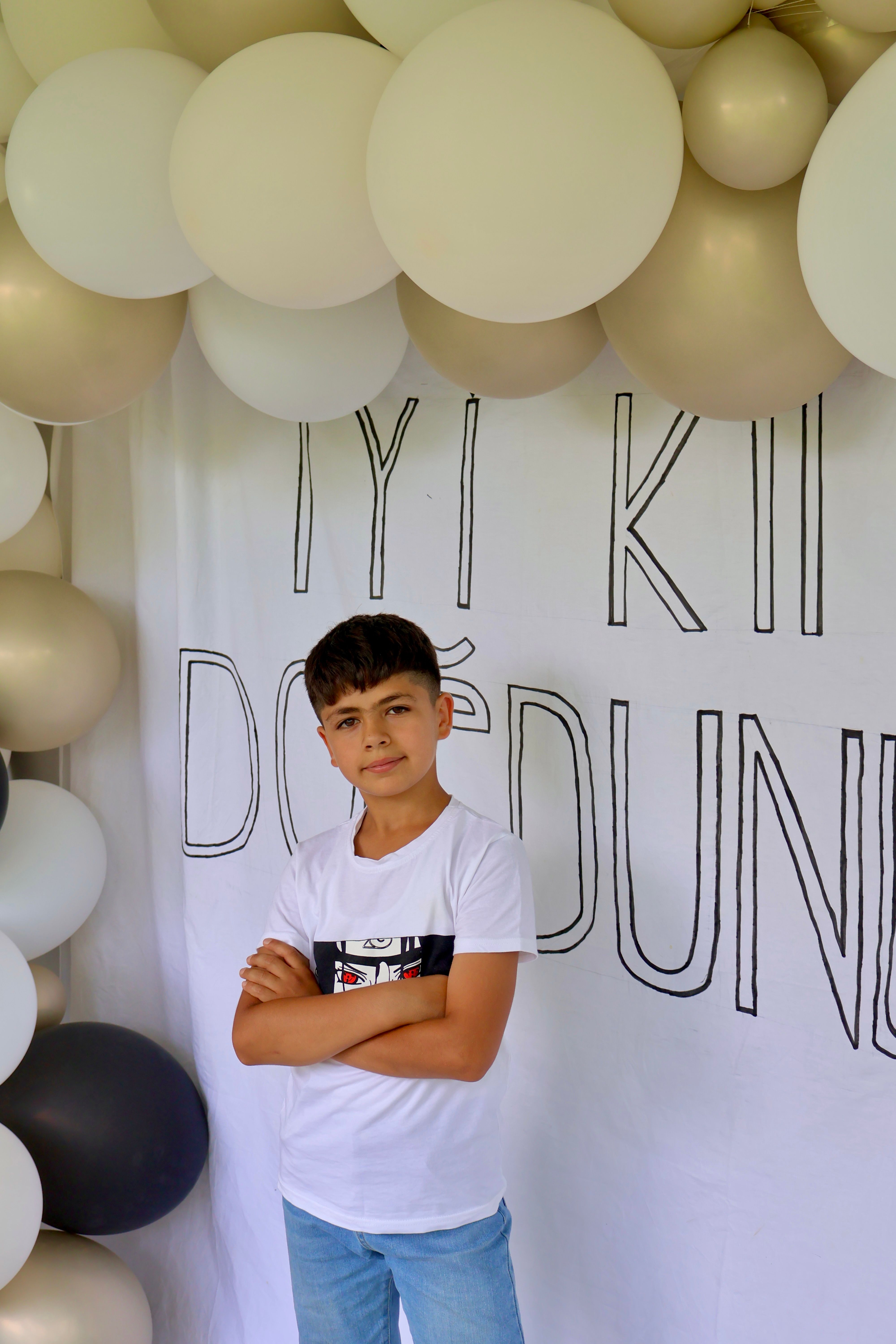 Boy posing at a birthday party with elegant balloon decorations.