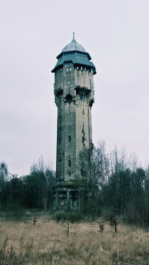 Free Old water tower surrounded by autumn trees under a cloudy sky. Captures rustic charm. Stock Photo