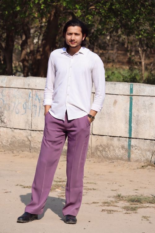 Free Young man in stylish purple pants posing confidently outdoors. Stock Photo