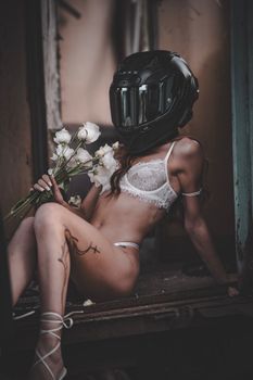 A woman in lingerie and helmet holds white flowers, blending elegance and surrealism.