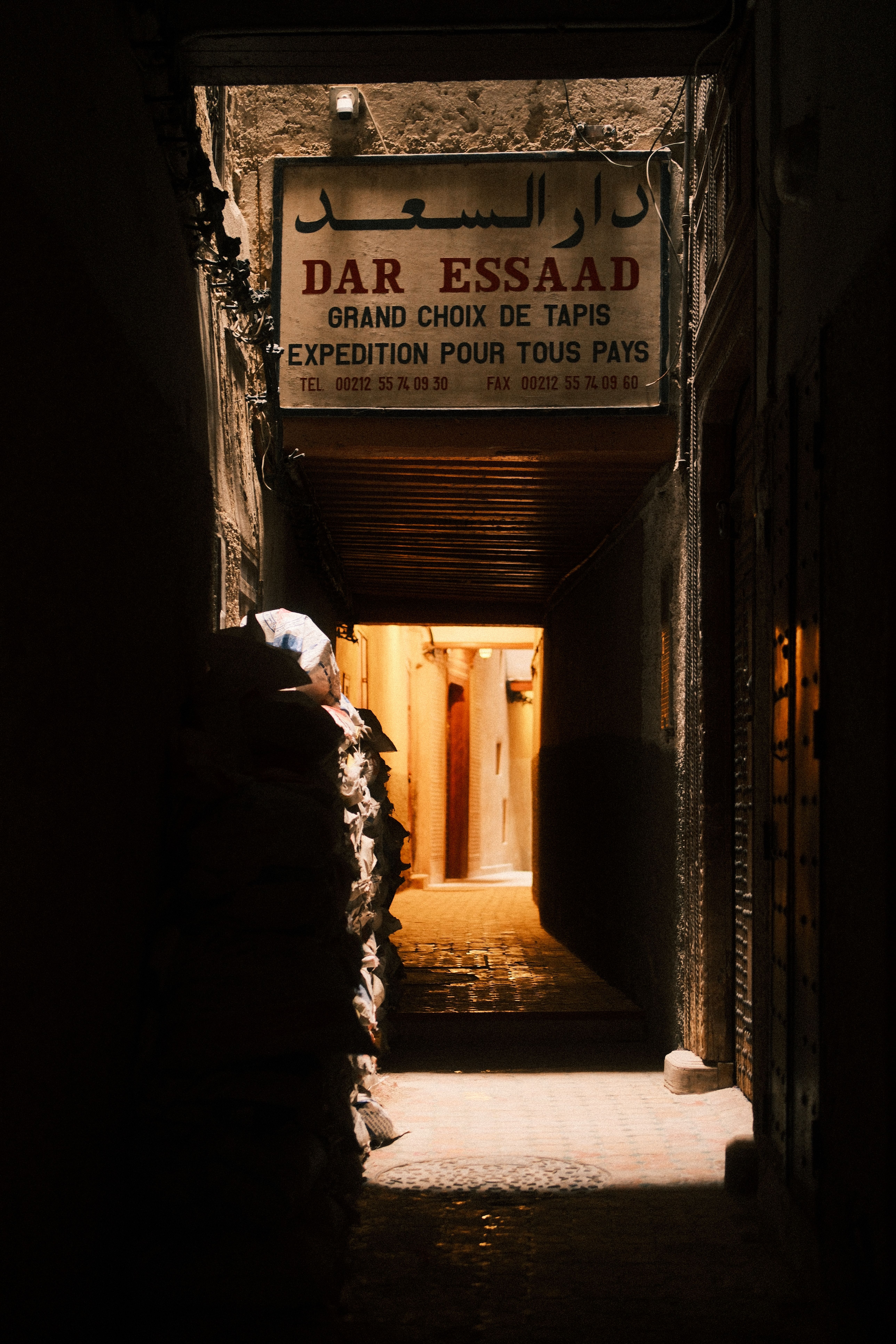 Cozy illuminated alley in Fes, Morocco, with a shop sign creating a warm, inviting atmosphere.