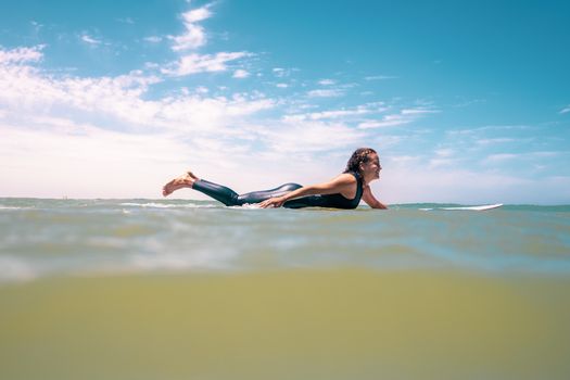 A woman paddles on a surfboard in the sunny waters of Oued Ed-Dahab-Lagouira, capturing the essence of ocean adventure.