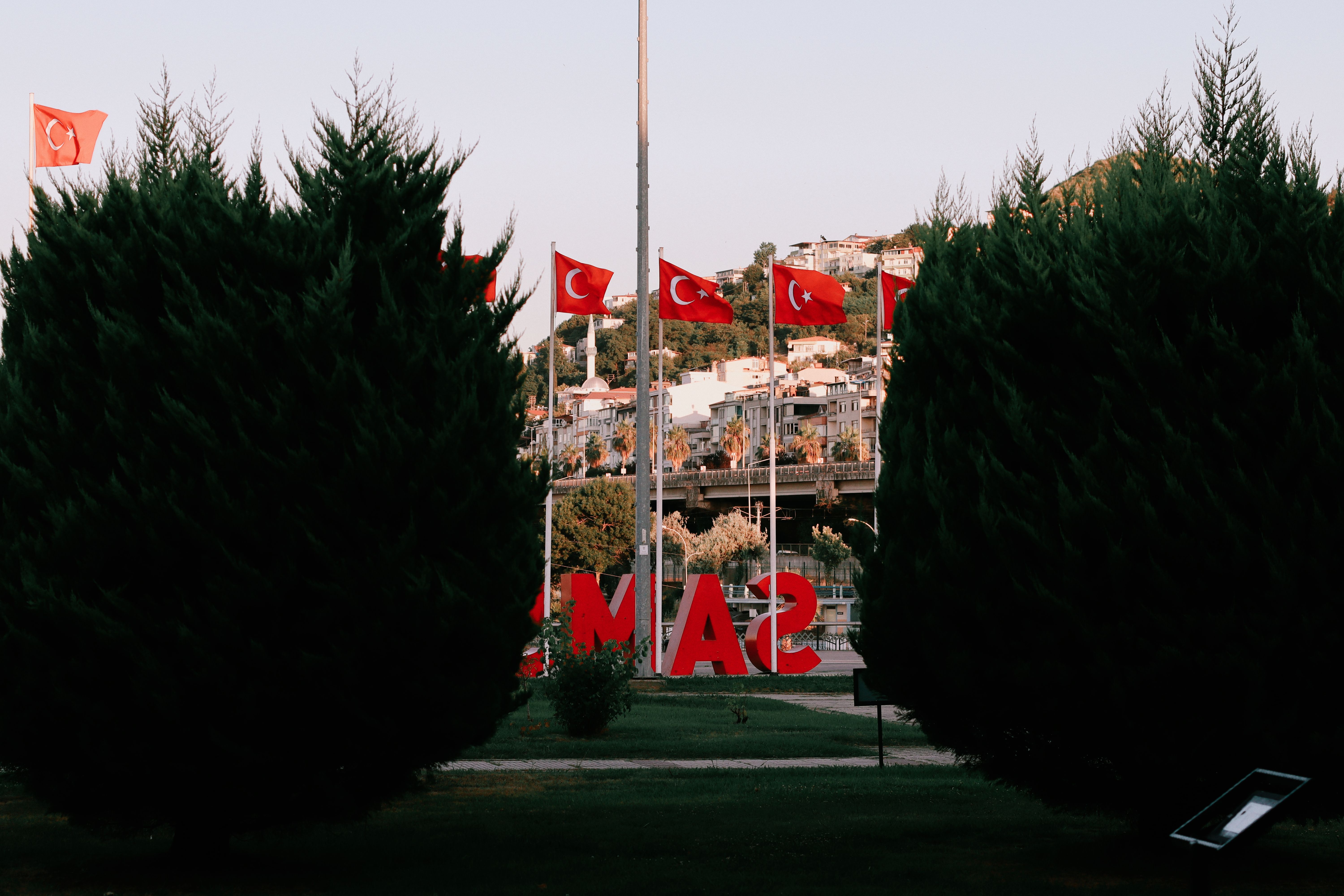 Samsun park scene with Turkish flags and hillside buildings, capturing city essence.