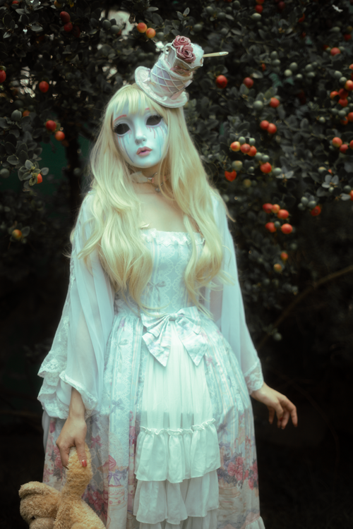 Free A whimsical portrait of a figure in a doll-like costume amidst a fantasy garden setting. Stock Photo