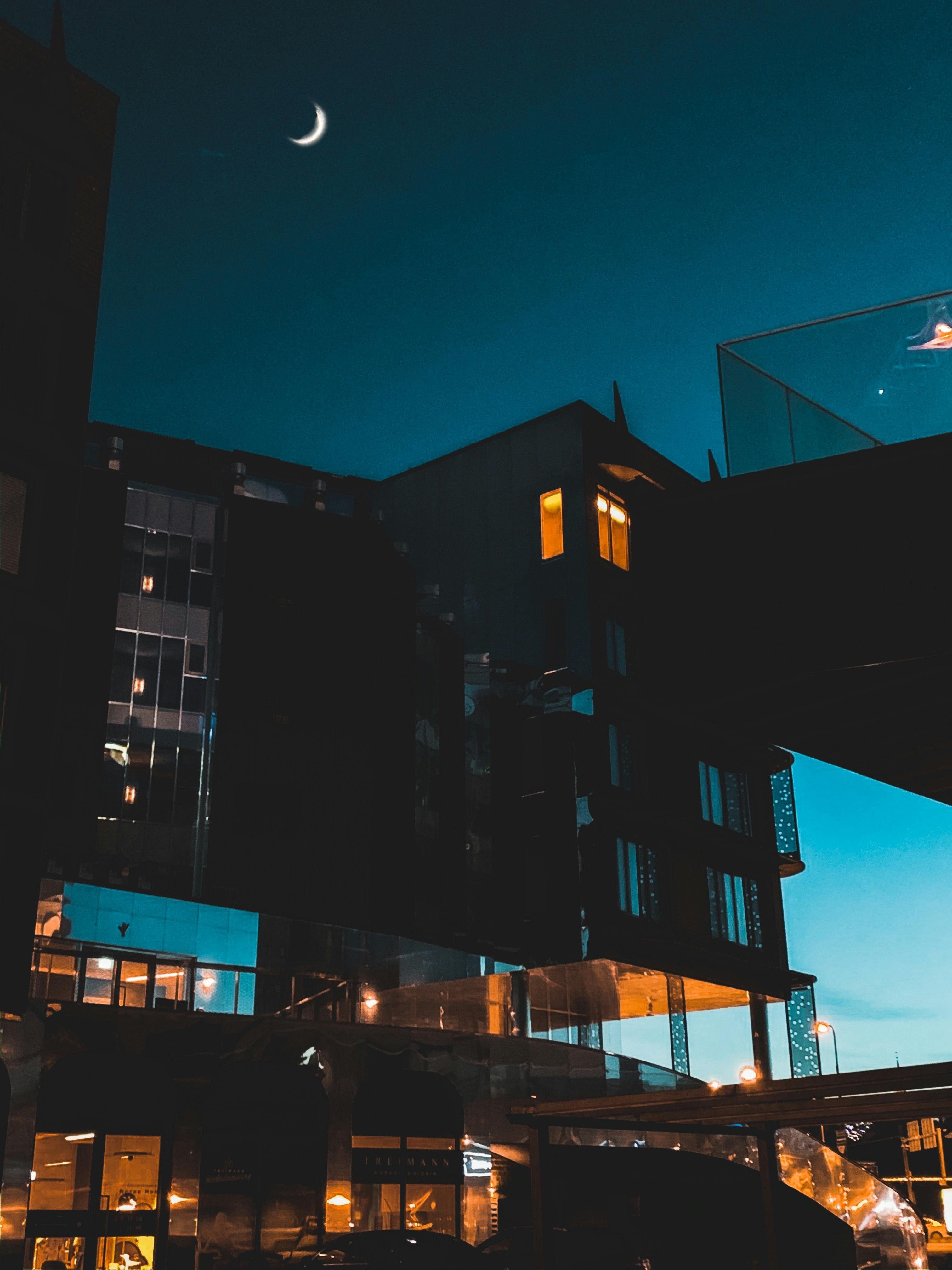 facades of modern buildings under night sky with moon