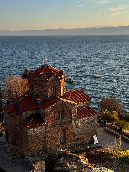Free Scenic view of St. John at Kaneo Church against the serene backdrop of Ohrid Lake at sunset. Stock Photo