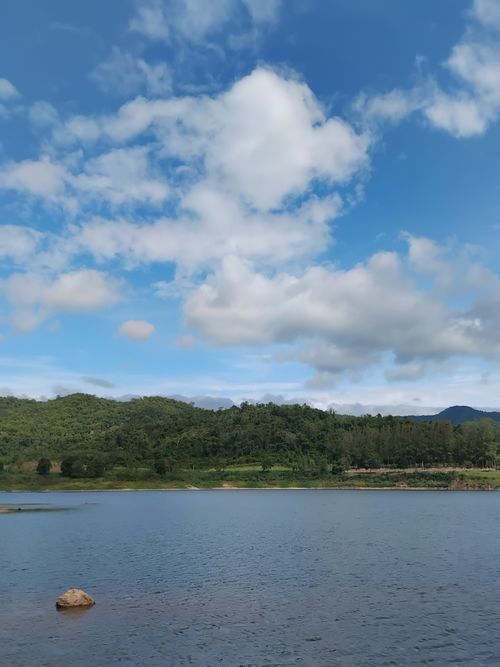 Free Tranquil lake view with lush green hills and bright blue skies, perfect for nature enthusiasts. Stock Photo