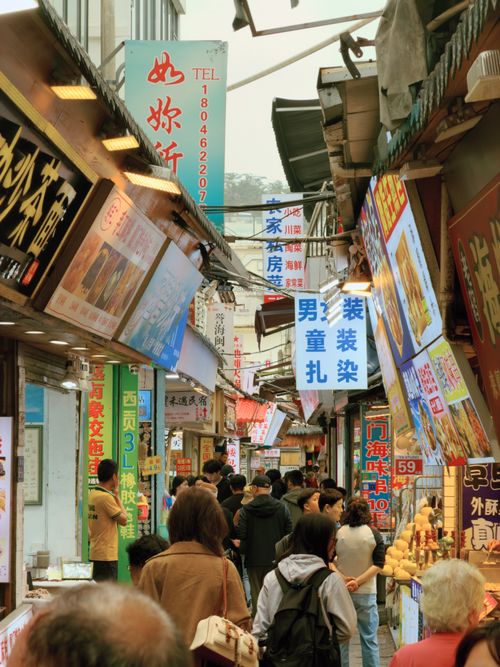 Free Busy market street with diverse crowd and colorful signage in an Asian city. Stock Photo