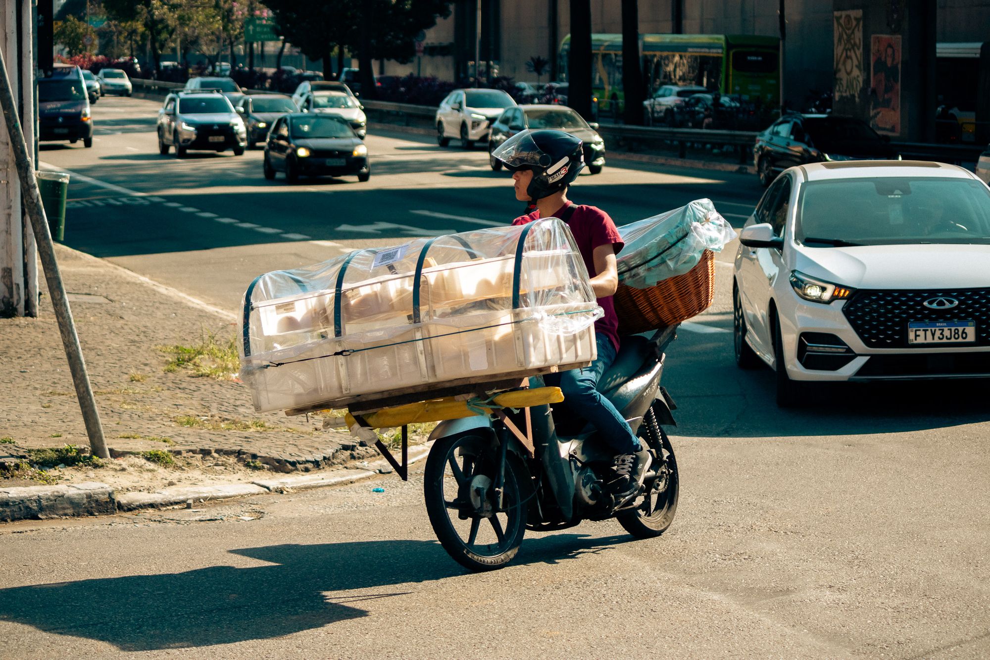Repartidor en motocicleta con caja térmica esperando en una calle de ciudad