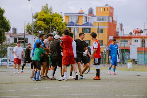 Free A group of teenagers playing soccer on an urban field, enjoying a lively and energetic sports match. Stock Photo