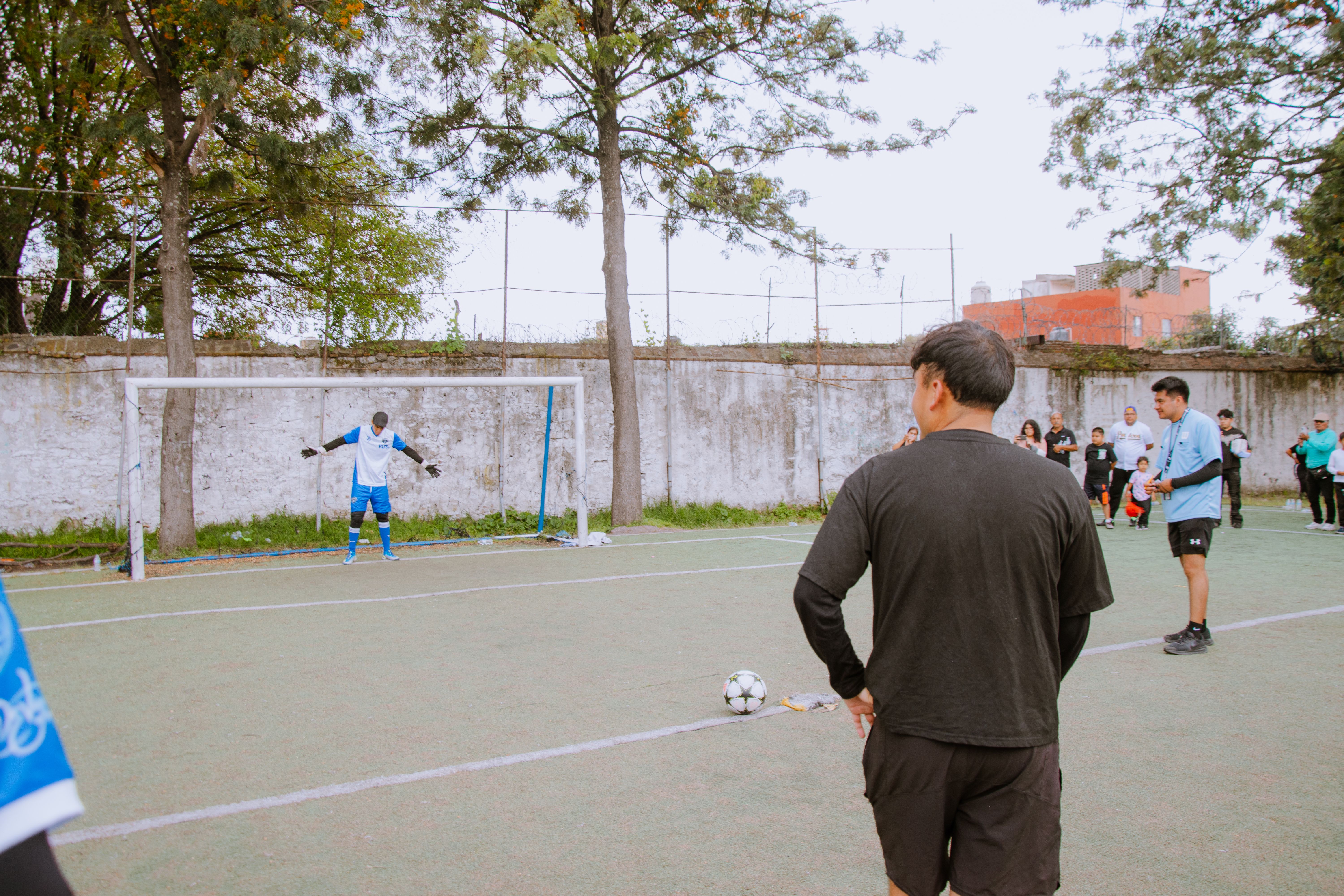 Amateur soccer game with players preparing for a penalty kick on a community field.
