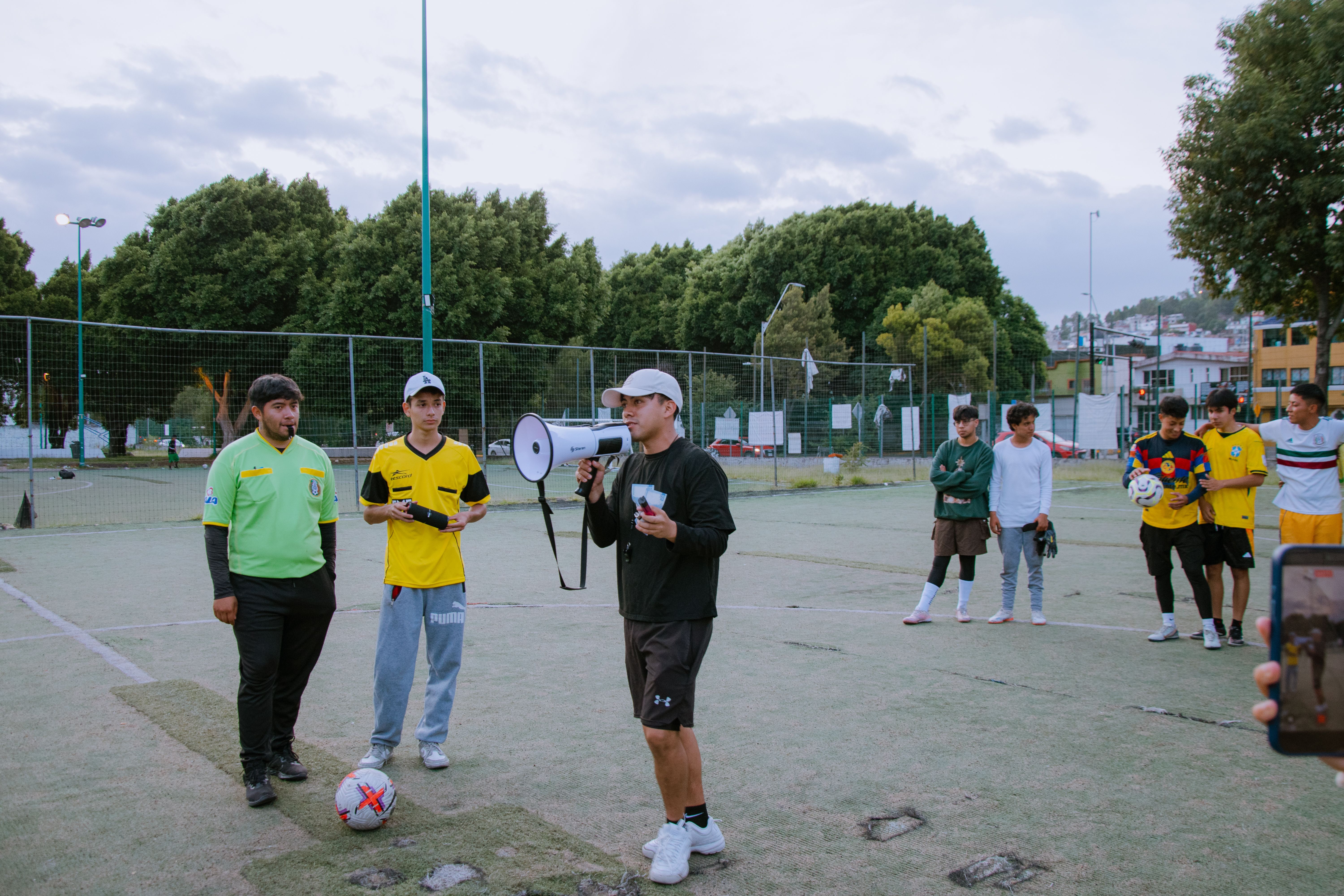 A soccer coach providing instructions to young players on a sunny outdoor field.