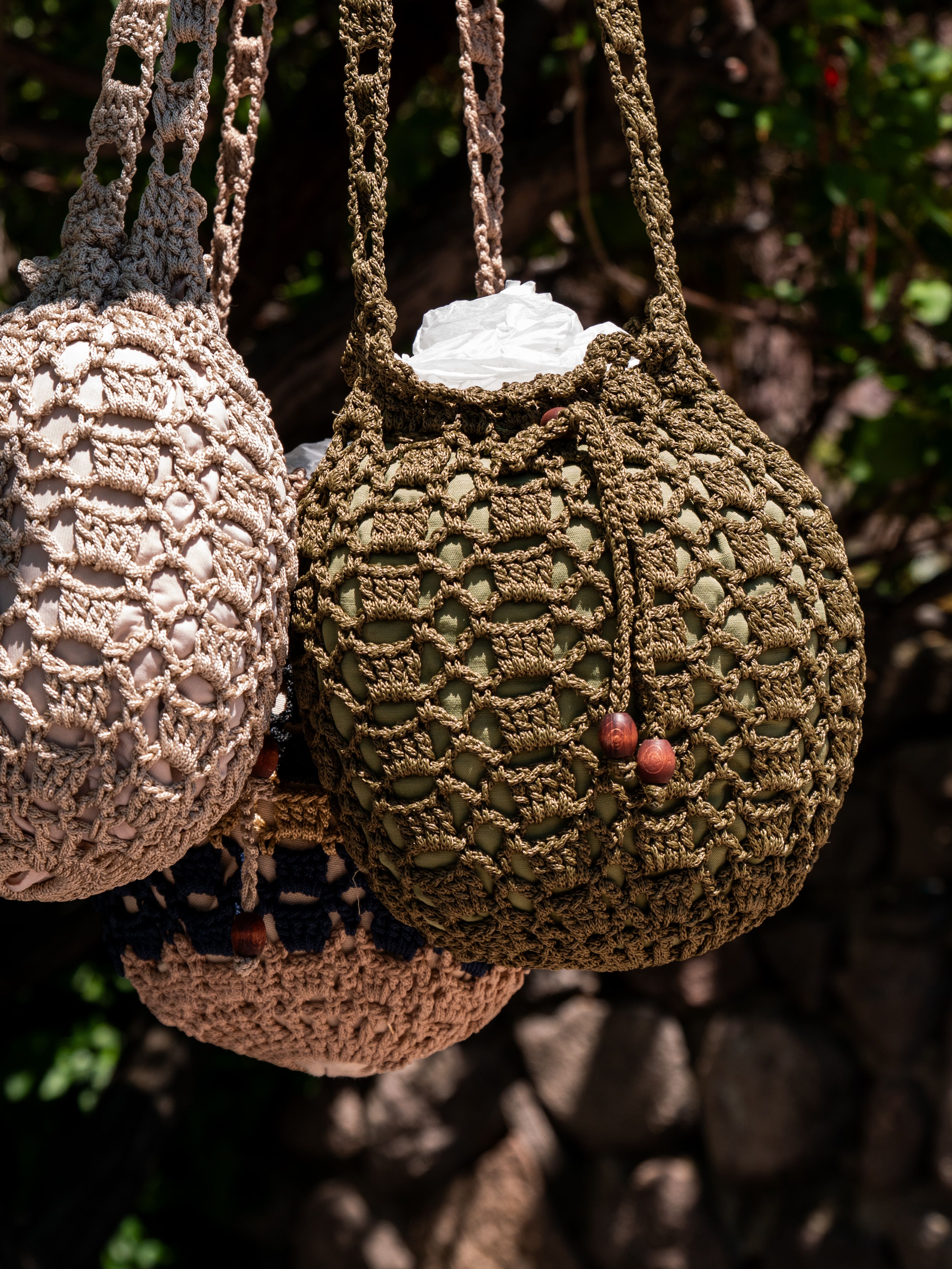 Bolsos de malla y crochet hechos a mano colgados a la luz del sol