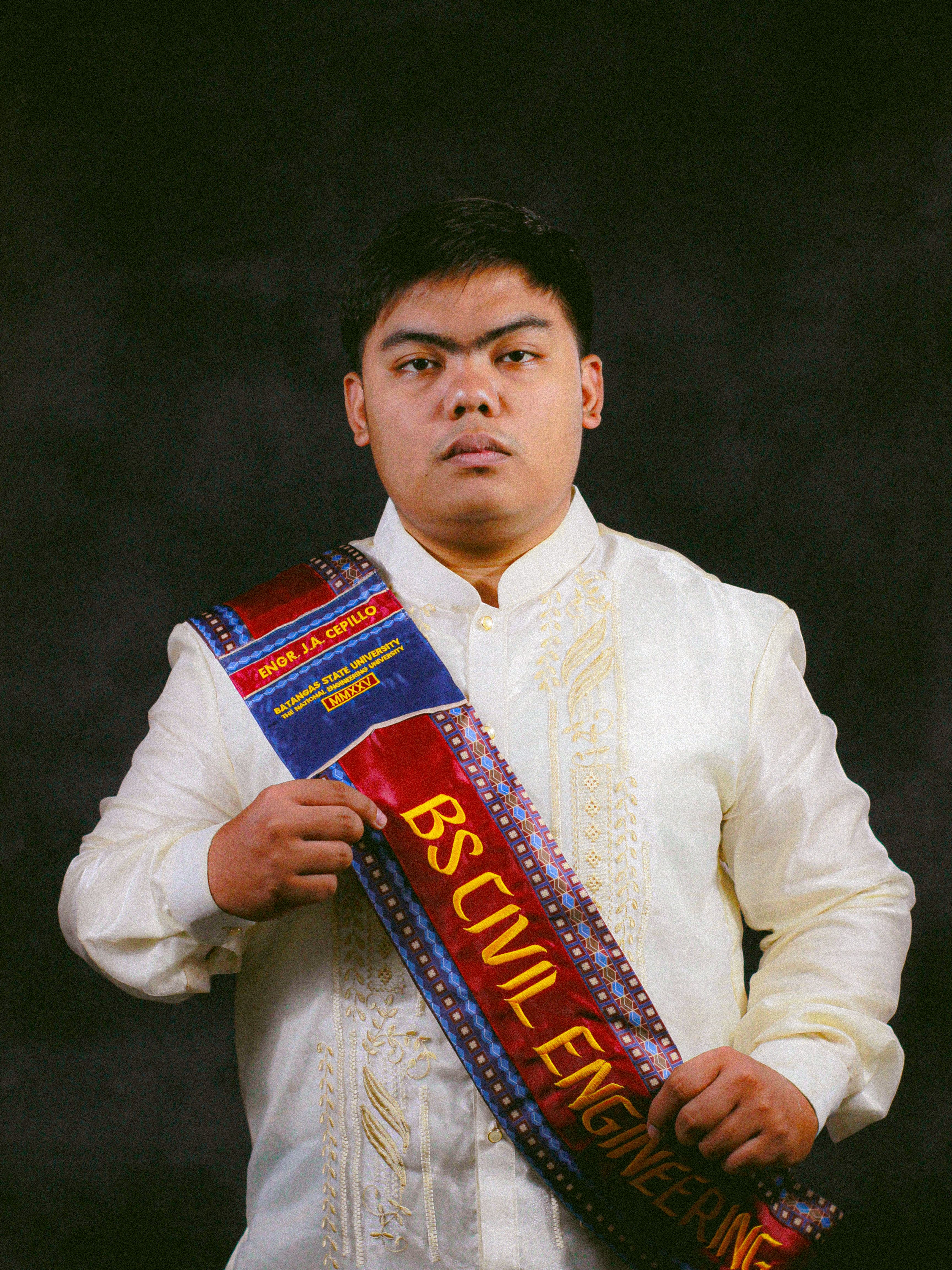 Portrait of a civil engineering graduate wearing traditional attire and graduation sash.