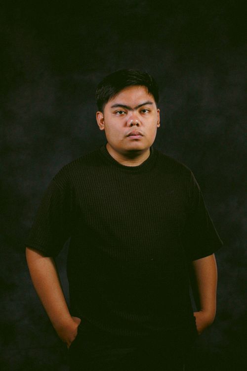 Free A contemplative portrait of a young man in a dark studio setting, exuding a serious and introspective mood. Stock Photo
