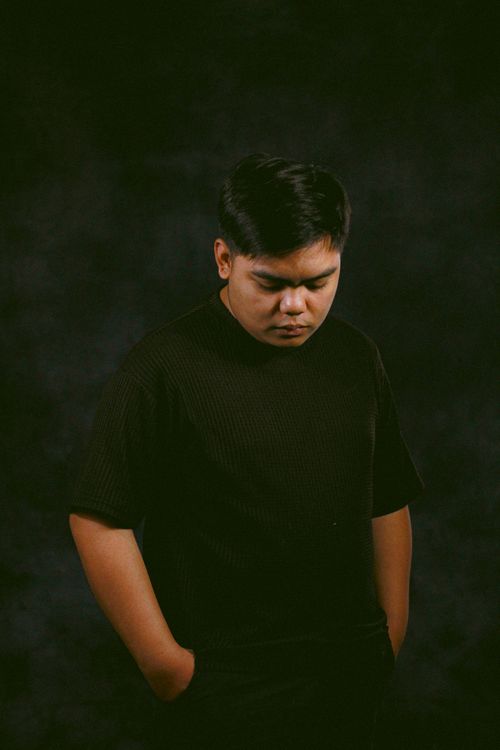 Free A young man with thoughtful expression against a dark backdrop, creating a moody atmosphere. Stock Photo