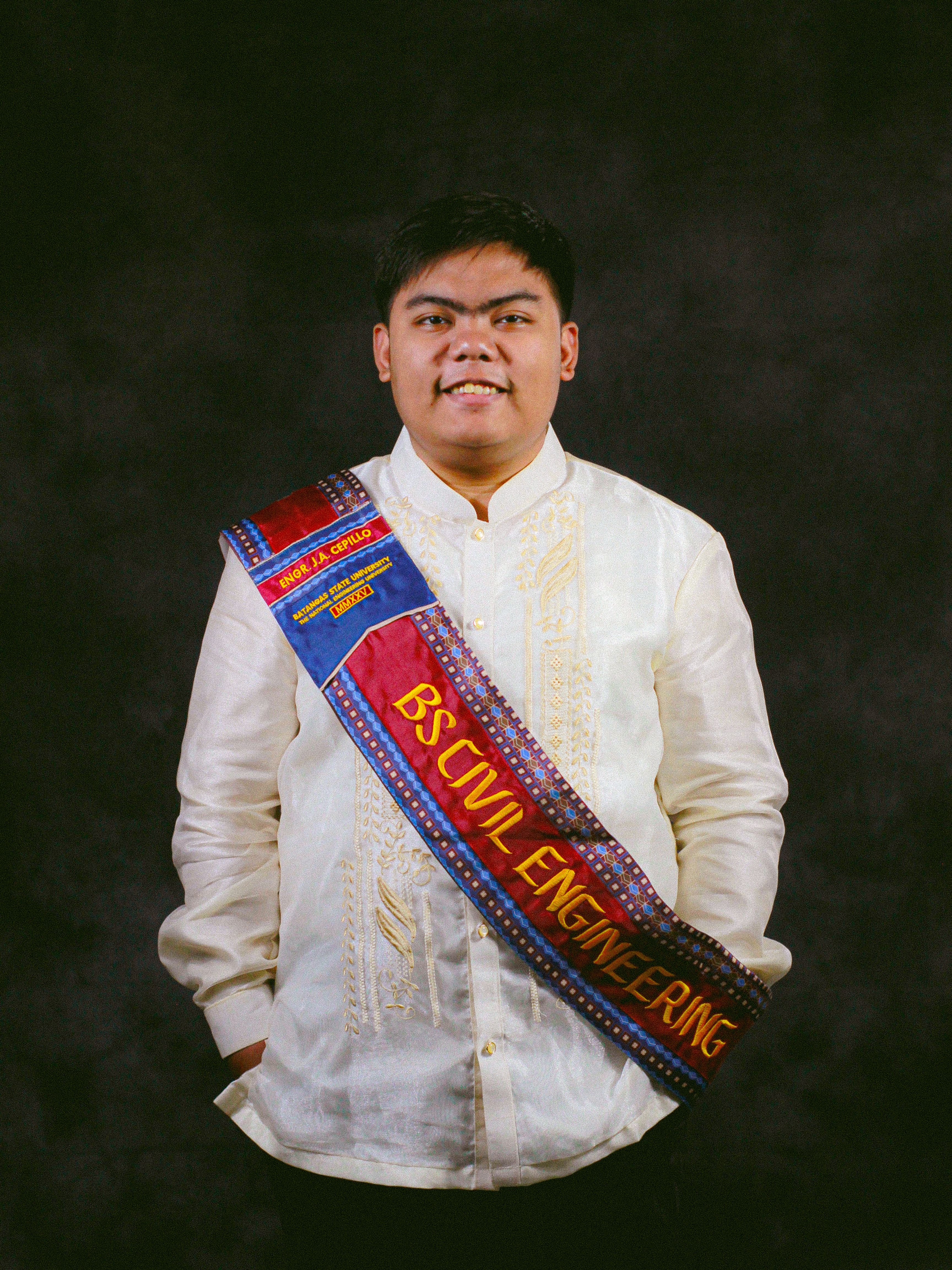 Portrait of a civil engineering graduate wearing traditional attire and a graduation sash.