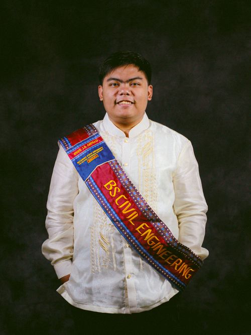 Free Portrait of a civil engineering graduate wearing traditional attire and a graduation sash. Stock Photo