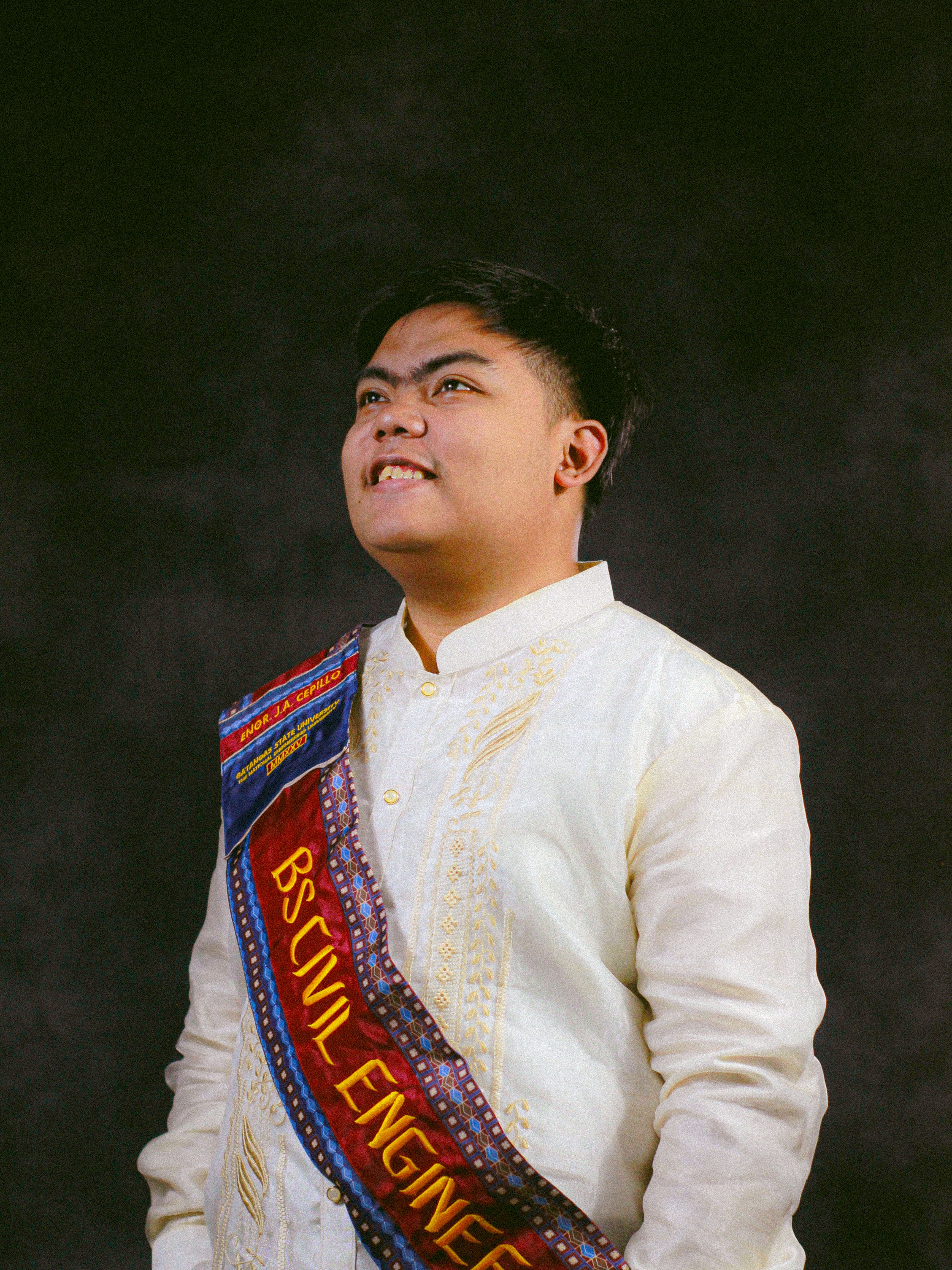 Portrait of a proud graduate in embroidered formal wear with a BS Civil Engineering sash.