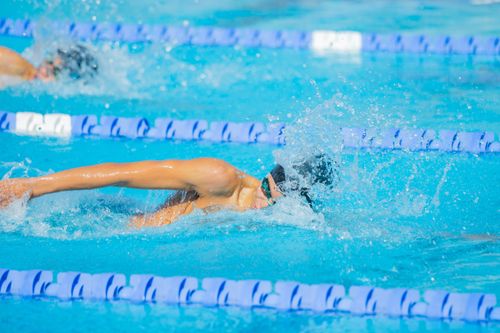 Free Swimmer performing freestyle stroke during competitive race in outdoor pool. Stock Photo