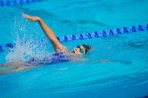 Free Young athlete swims backstroke in outdoor pool during sunny day competition. Stock Photo
