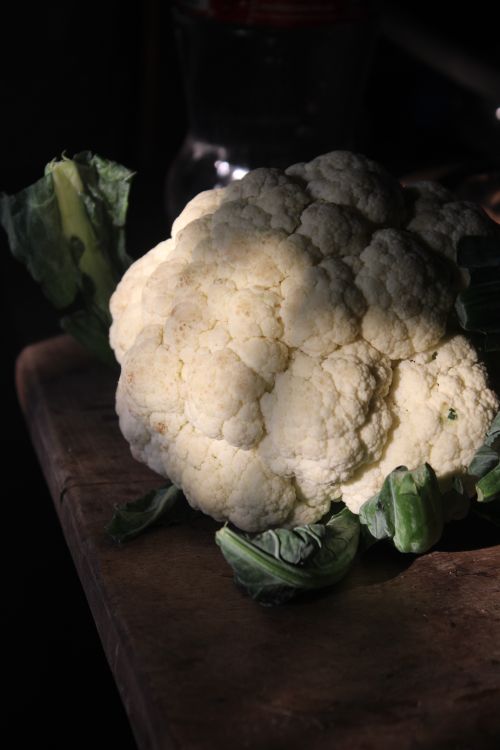 Free Fresh cauliflower with leaves on a rustic wooden surface, in natural light. Stock Photo