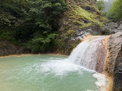 Free A tranquil waterfall cascading into a turquoise pool surrounded by lush greenery. Stock Photo