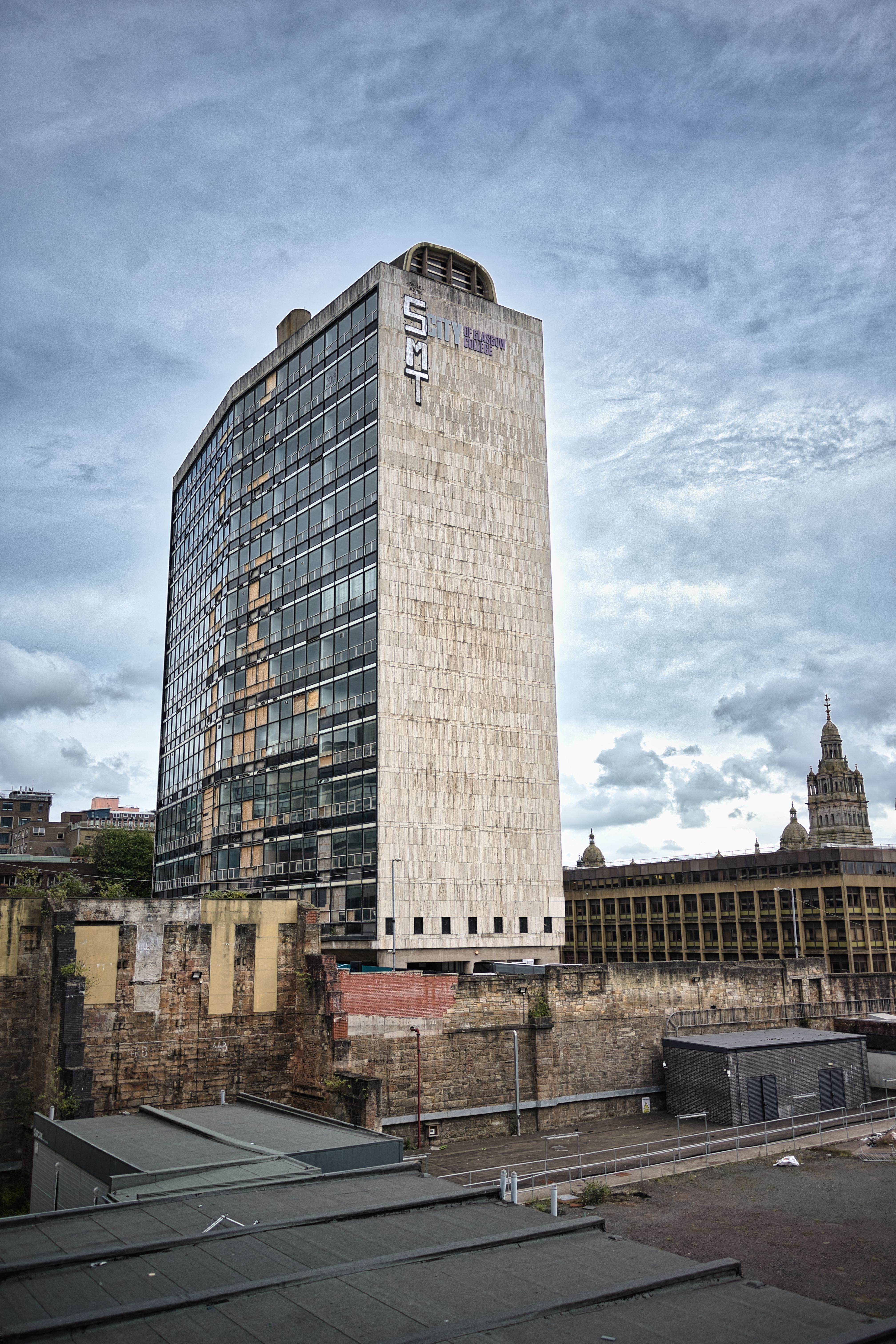 A tall urban building against a dramatic cloudy sky in a cityscape.