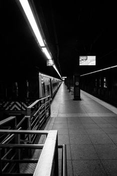 Black and white photo capturing a quiet New York subway platform.