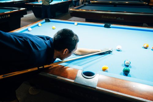 Free A man skillfully playing billiards, focusing on his shot on a pool table. Stock Photo