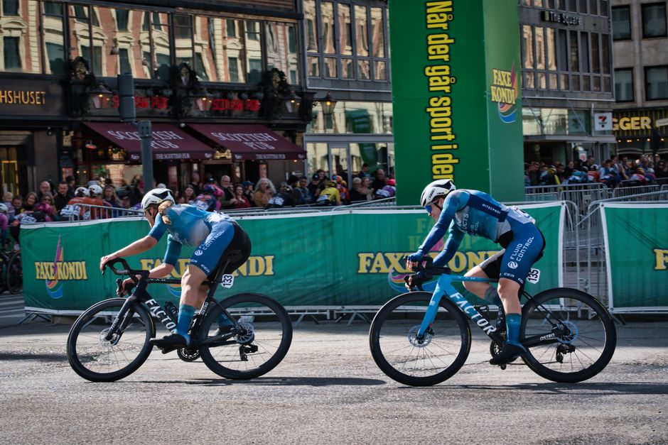 Dynamic scene of cyclists racing in Copenhagen with spectators and city backdrop.