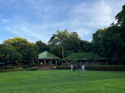 Free Serene landscape with large green lawn, trees, and rustic house under clear sky. Ideal for nature themes. Stock Photo