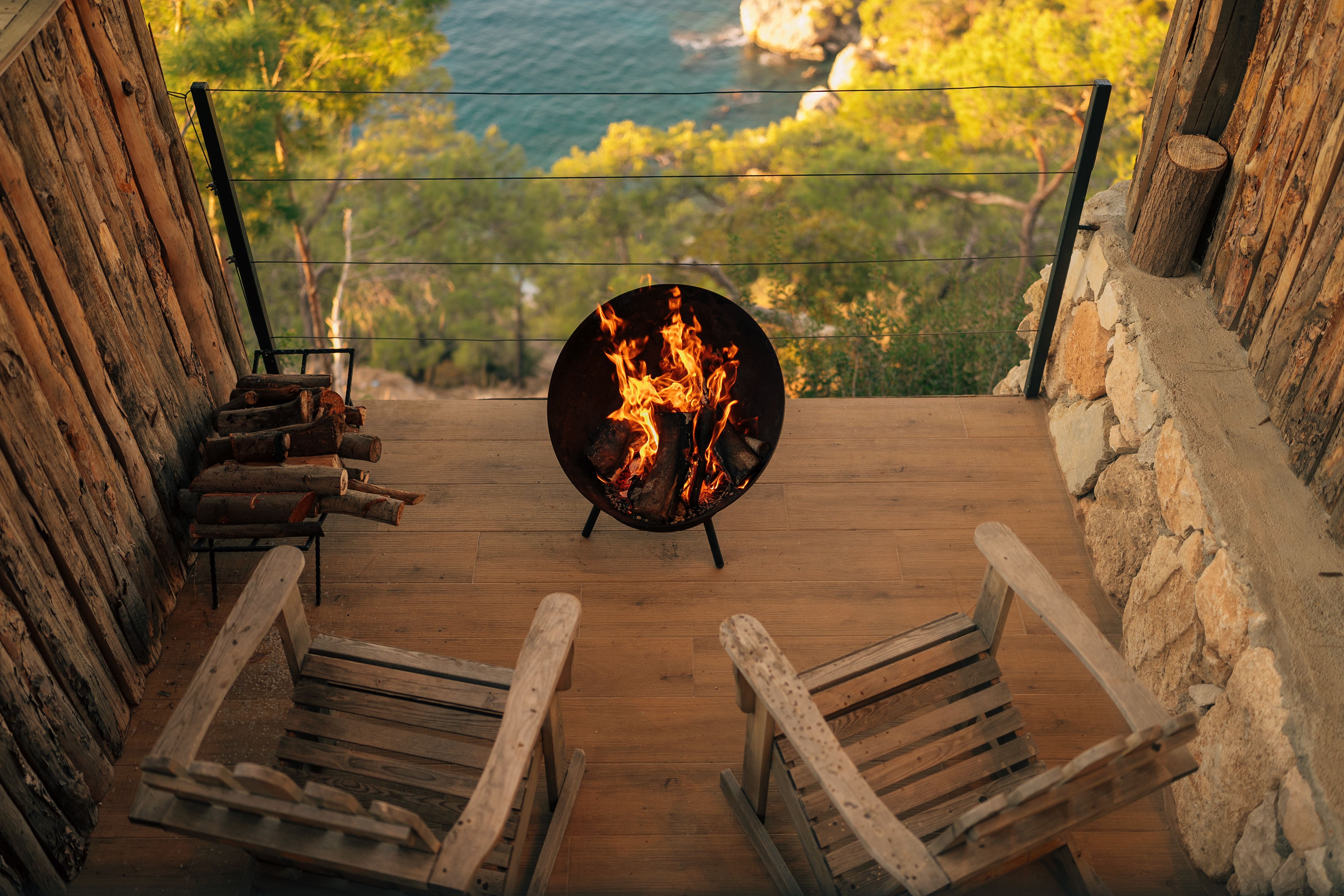 Inviting view from a wooden terrace with fire pit overlooking the sea in Antalya, Türkiye.