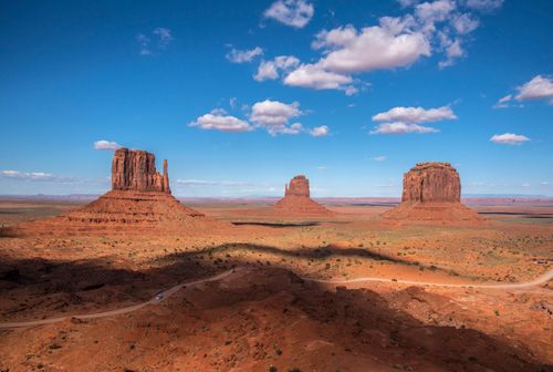 Free Stunning view of Monument Valley buttes against a clear blue sky and scattered clouds. Stock Photo