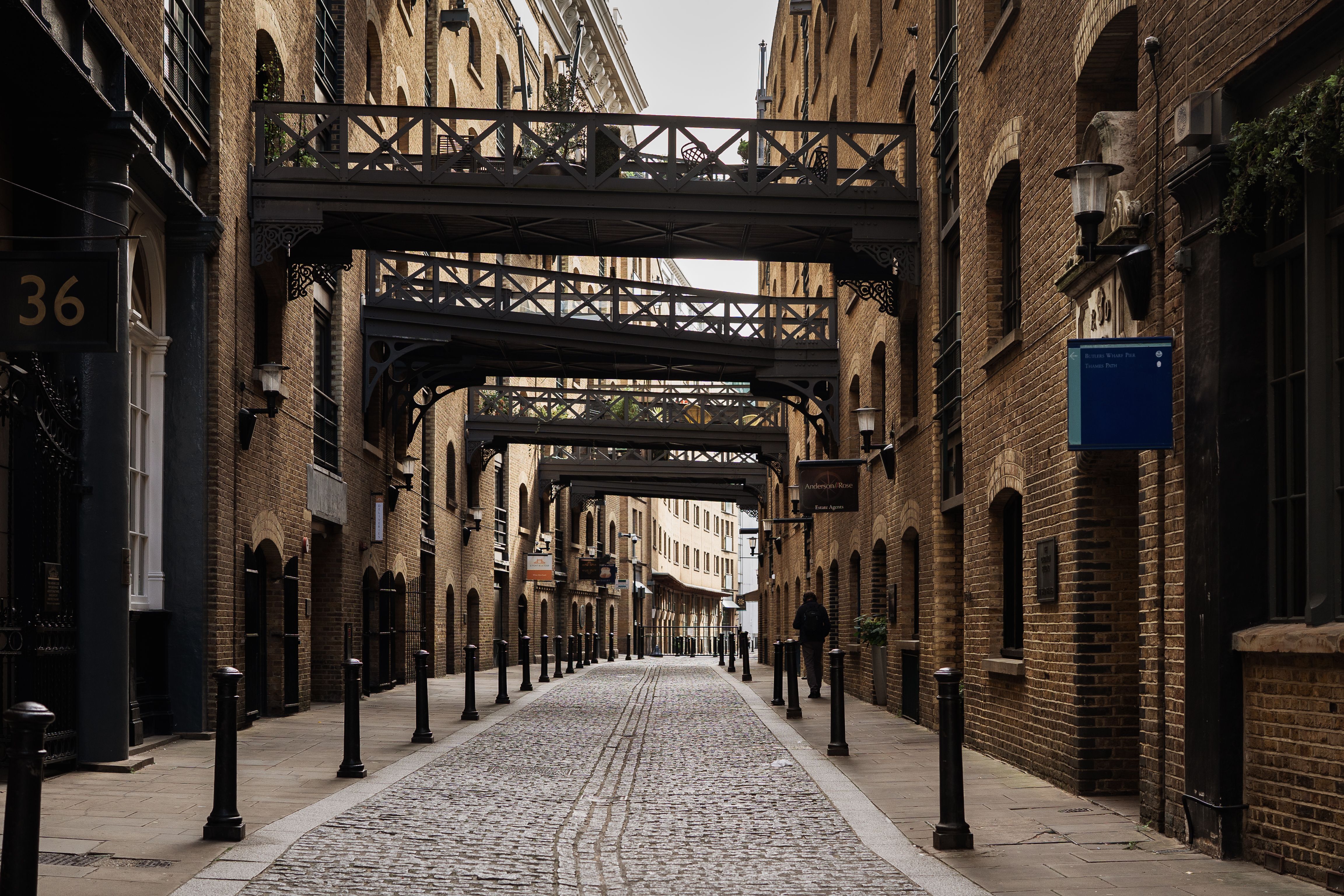 View of a historic London alley with iron walkways and cobblestone path, capturing urban charm.
