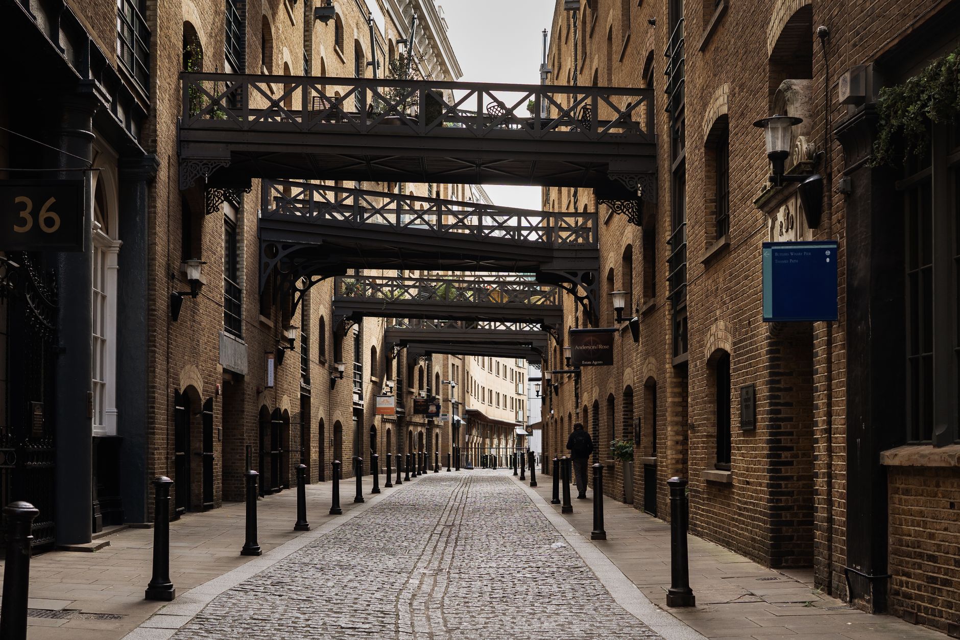View of a historic London alley with iron walkways and cobblestone path, capturing urban charm.
