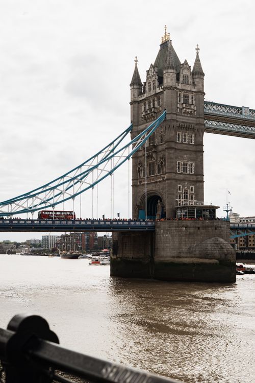 Free View of London's iconic Tower Bridge with a classic red bus crossing over the Thames River. Stock Photo