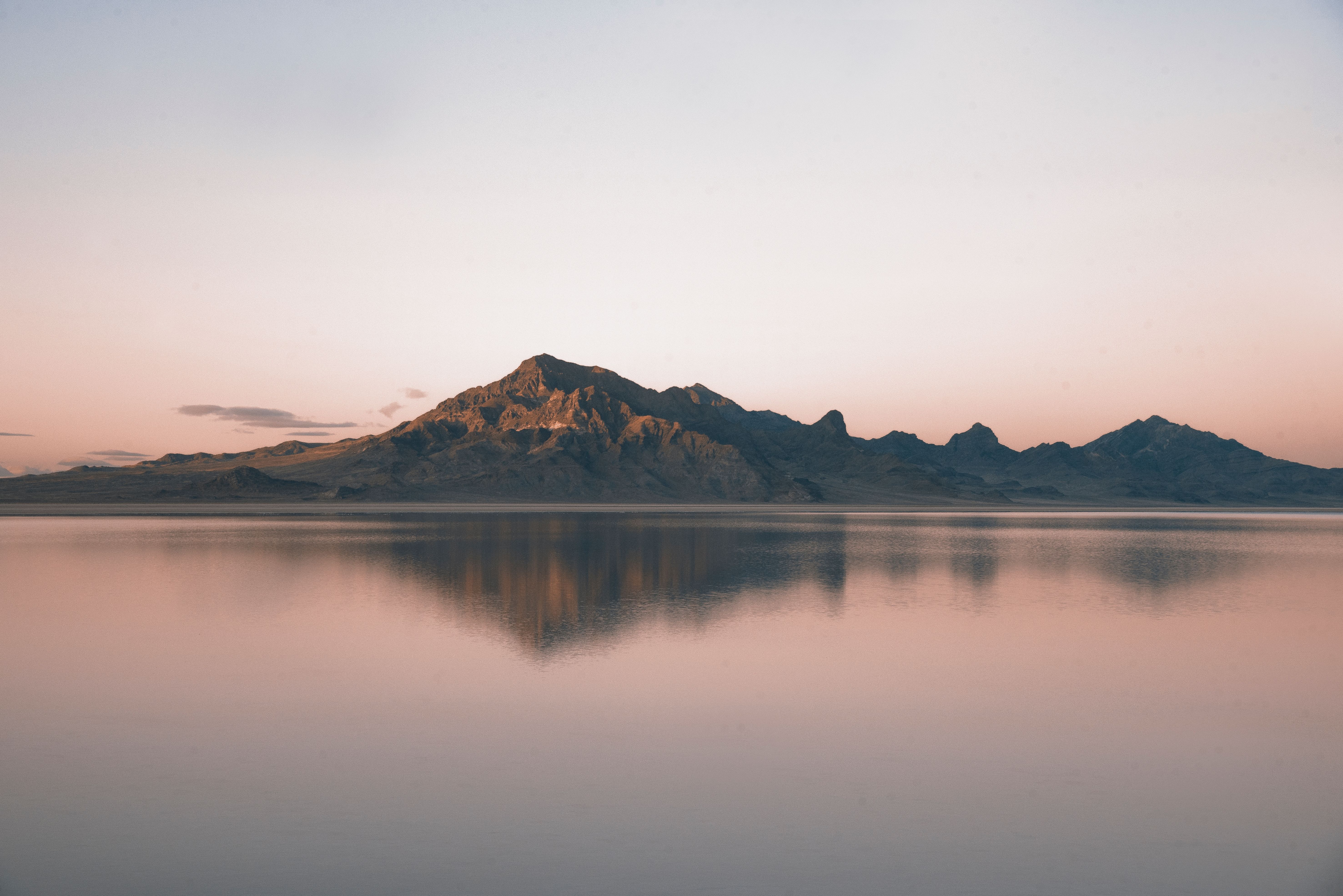 Tranquil mountain landscape with mirrored reflection in calm water at sunrise.