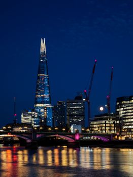 Stunning nighttime cityscape of The Shard and London skyline with reflections in the Thames.