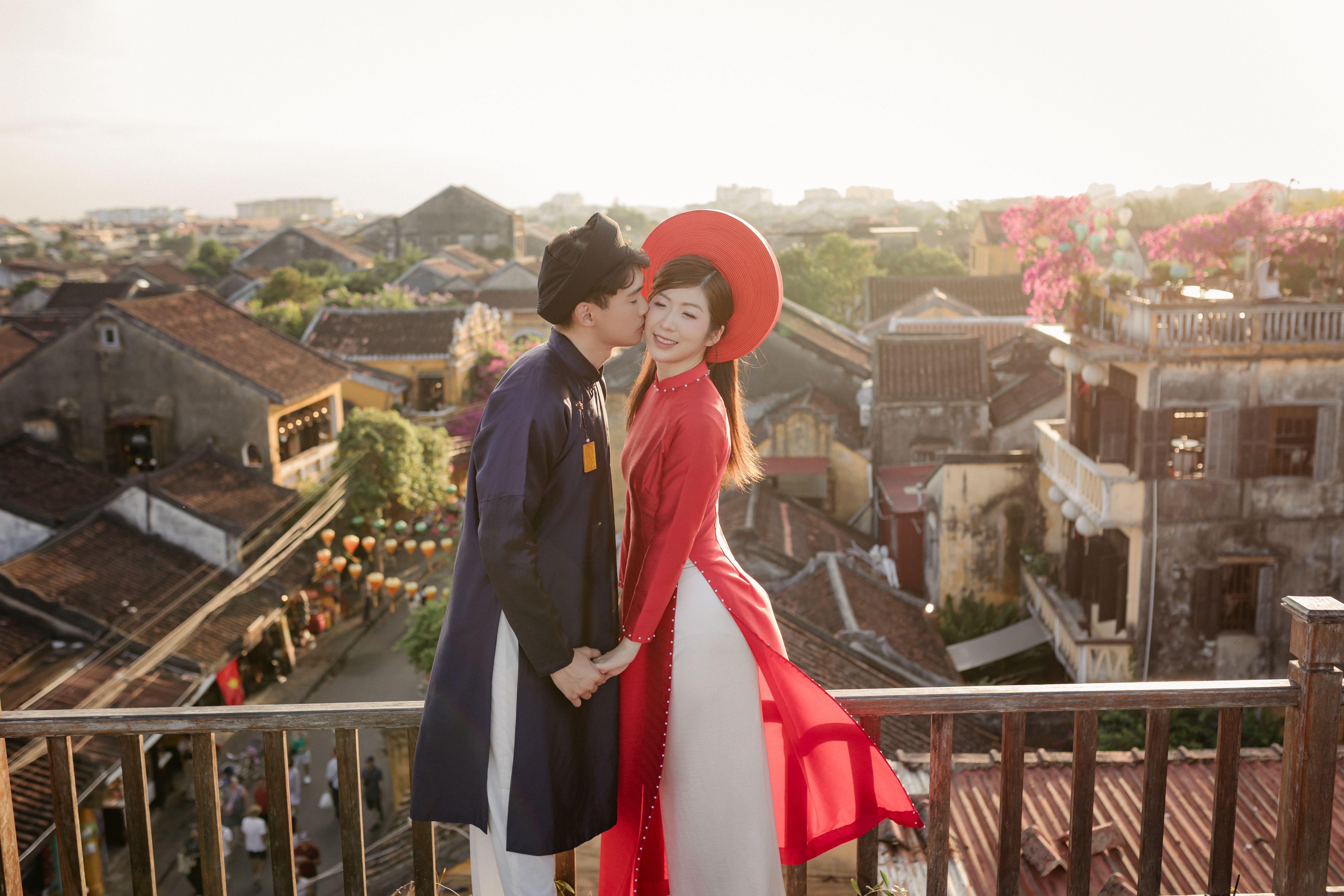 A couple in traditional Vietnamese clothing shares a romantic moment overlooking Đà Nẵng's historic architecture.