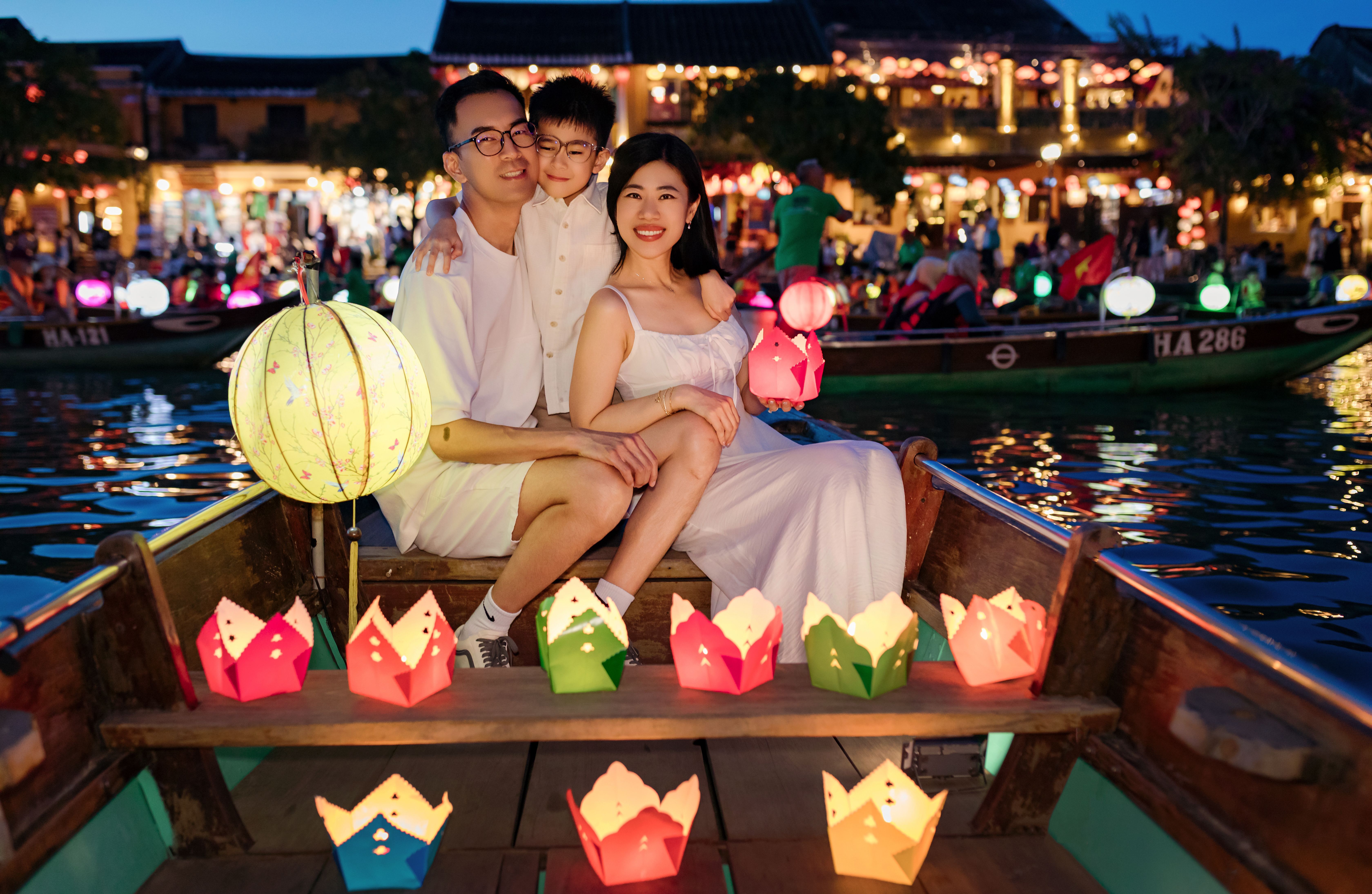 A joyful family enjoying the colorful lantern festival on a boat in Đà Nẵng, Vietnam.