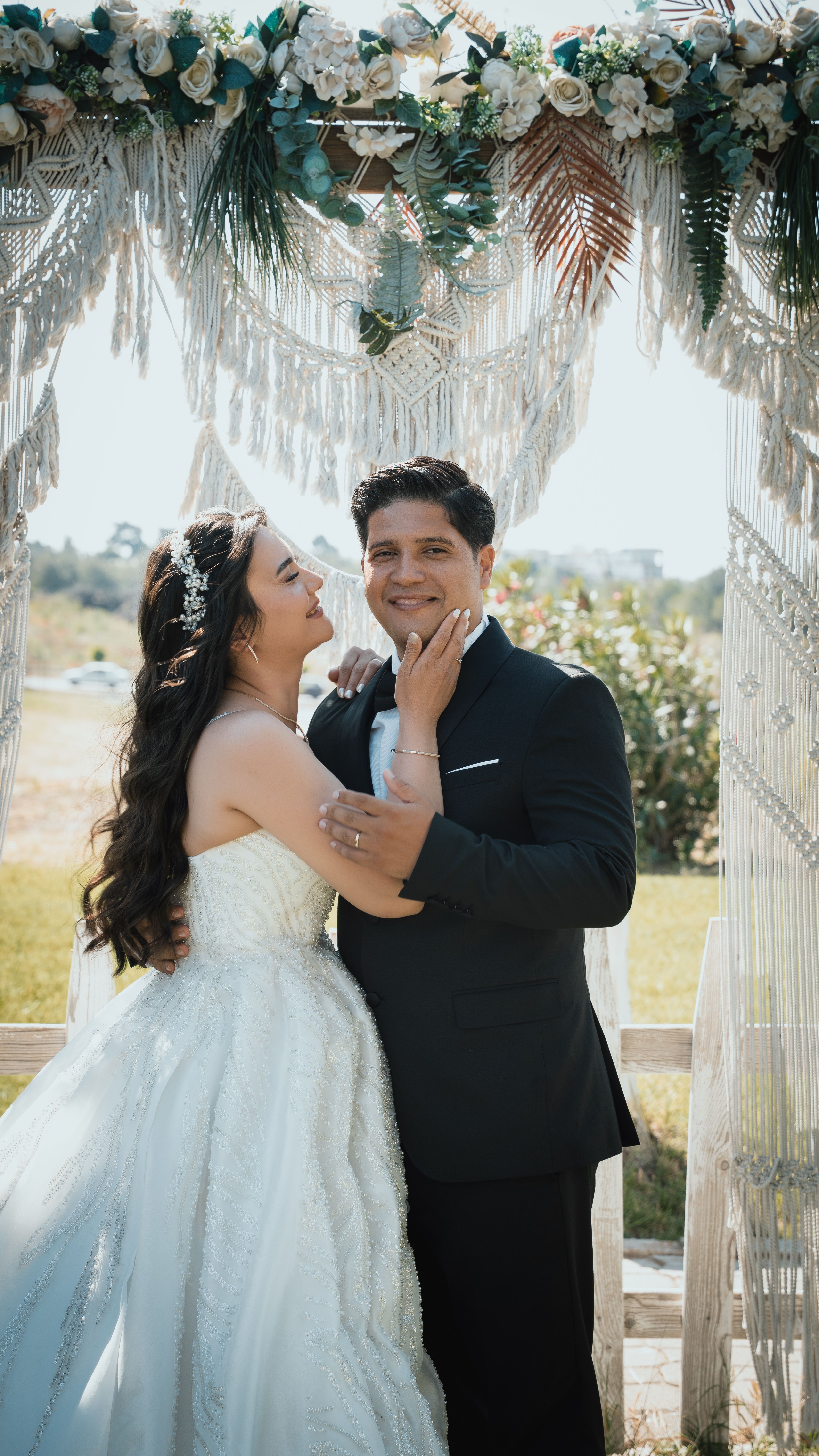 A joyful bride and groom embracing under a floral archway during their outdoor wedding in Ankara.