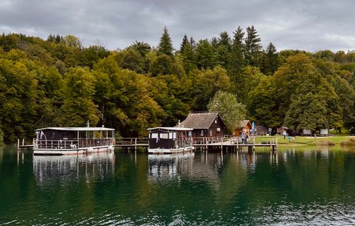 Free Tranquil lake scene with boats docked by a rustic cabin in scenic autumn forest. Stock Photo