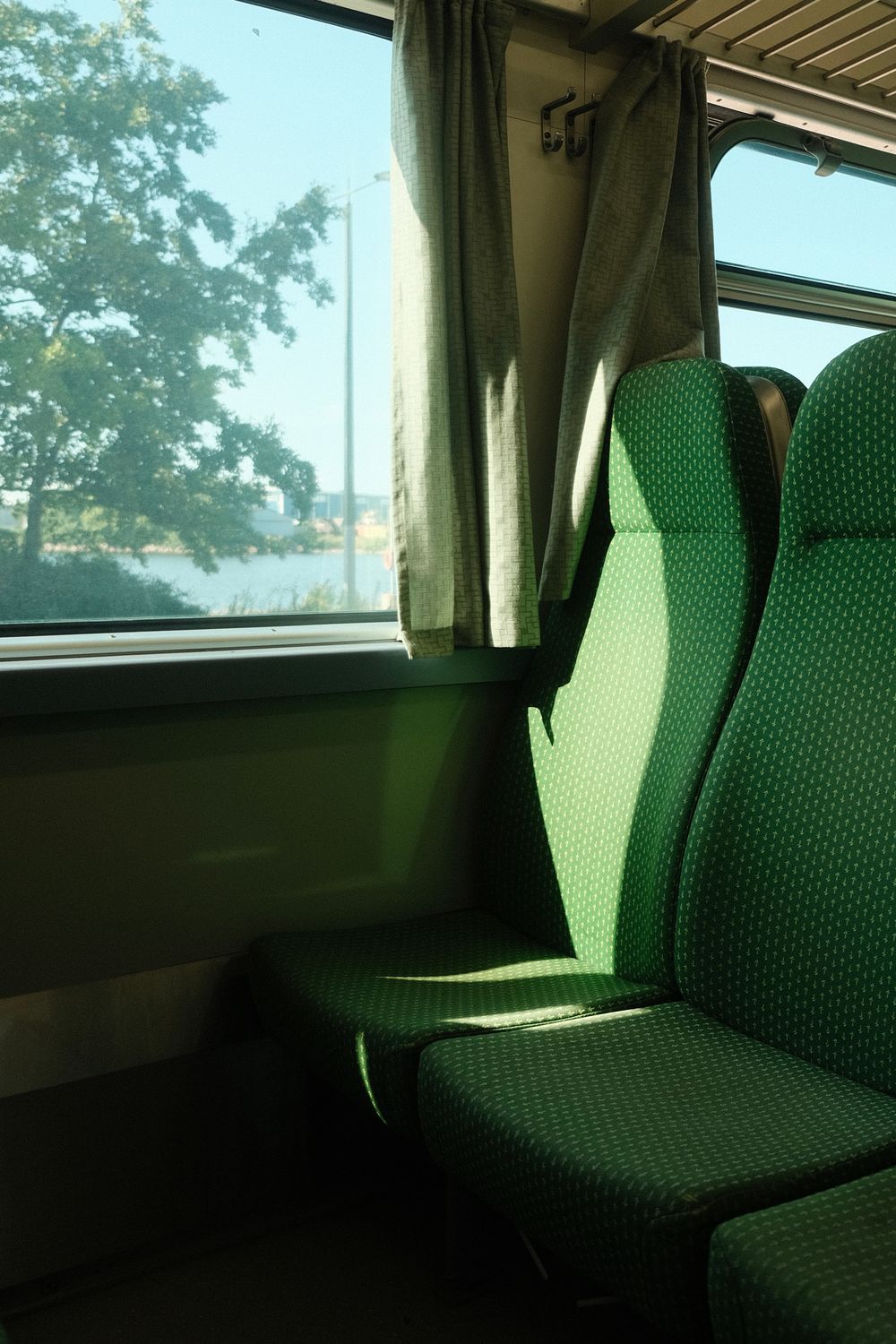 Loc la fereastra unui tren, cu lumina soarelui pe scaun