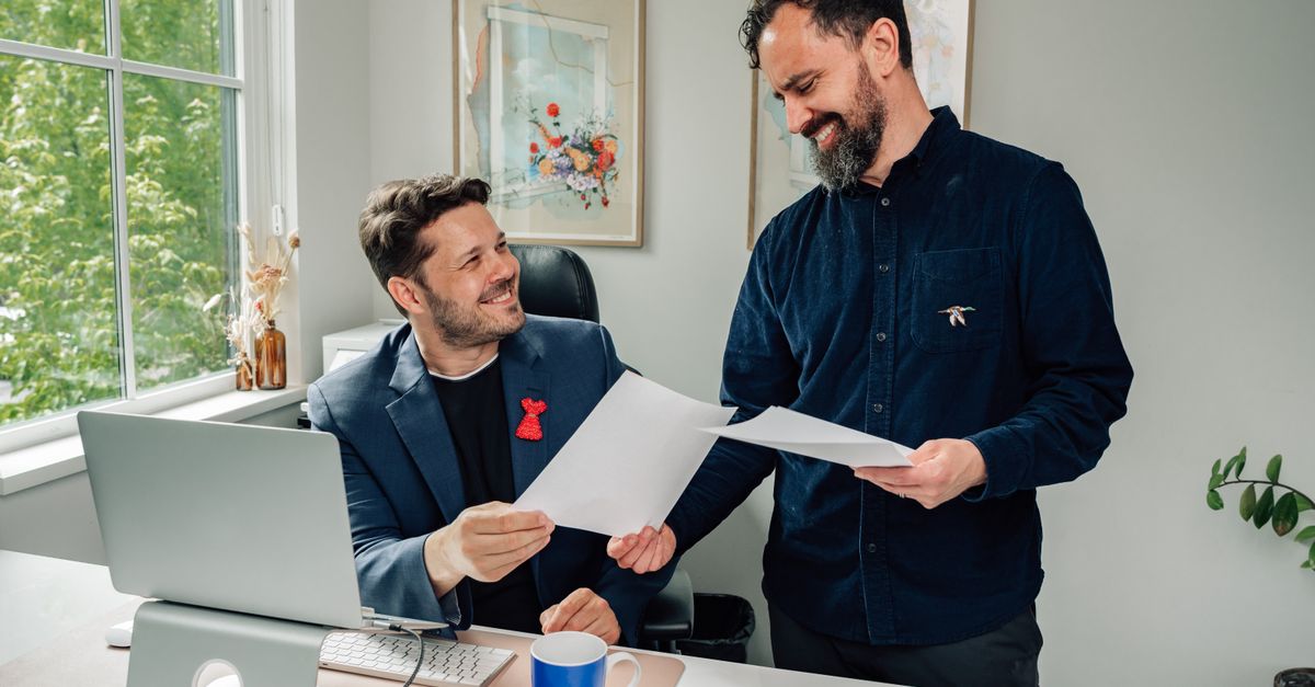 Two business professionals discussing documents in a bright, modern office setting.